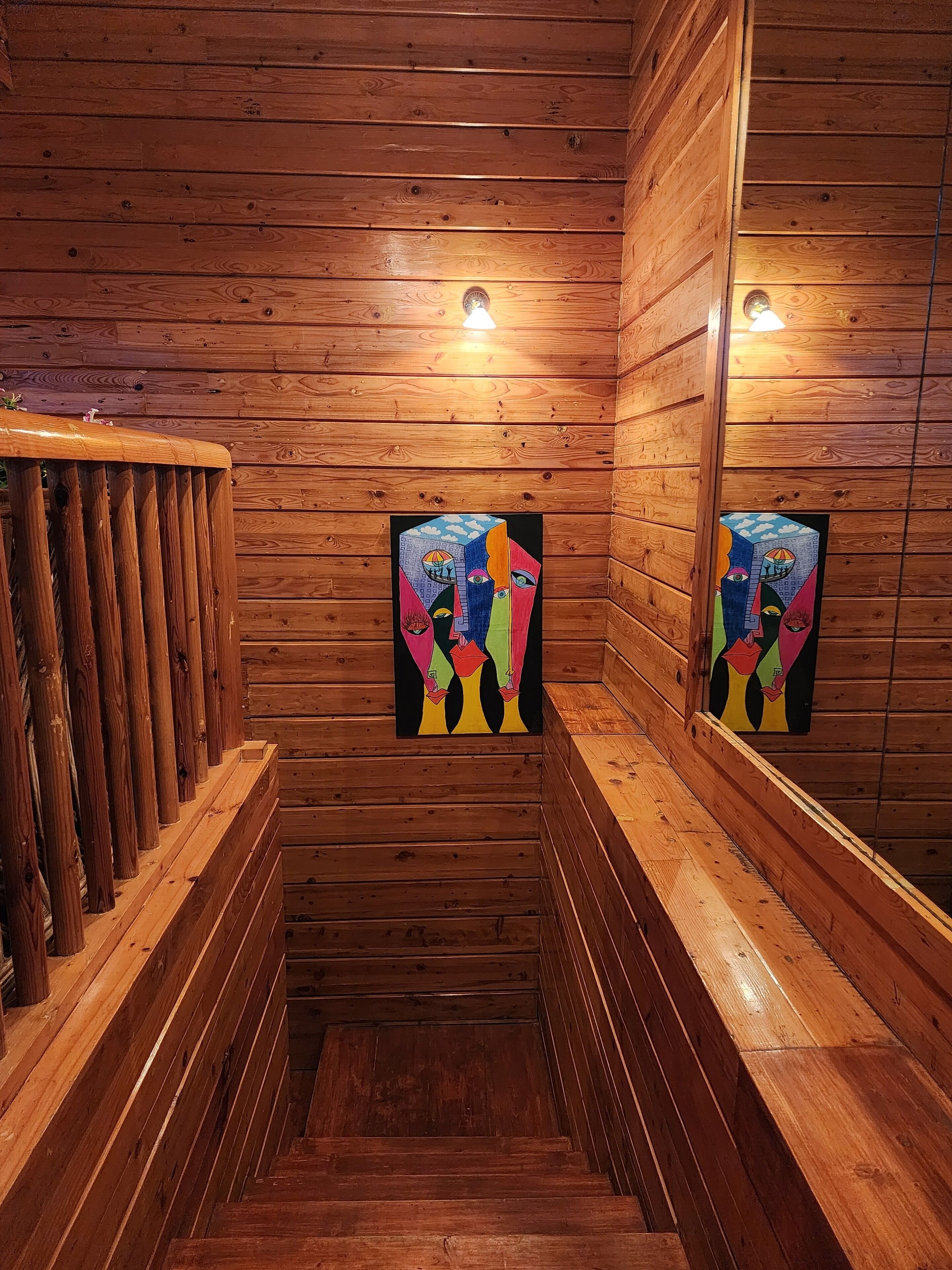 Una escalera de madera con barandilla de madera a la izquierda y un cuadro en la pared.