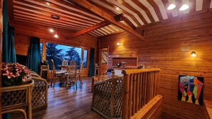 Interior de una cabaña de madera con comedor, cocina y escalera.