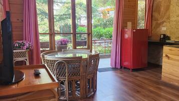 A wooden interior with a dining area, a red refrigerator, and large windows.