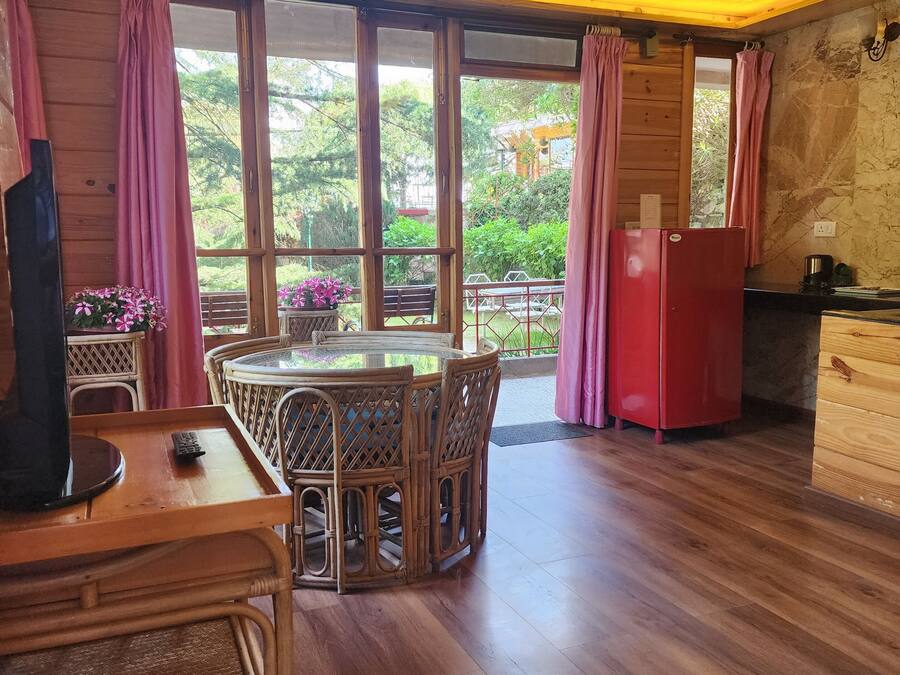 A wooden interior with a dining area, a red refrigerator, and large windows.