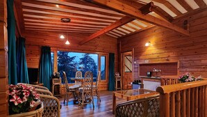 Interior acogedor de una cabaña con comedor de madera, cocina y vistas al exterior.