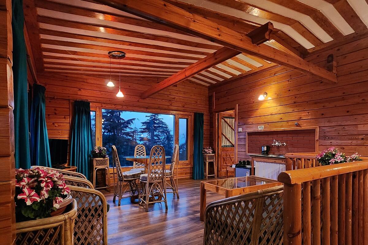 A cozy cabin interior with a wooden dining area, a kitchen, and a view of the outdoors.