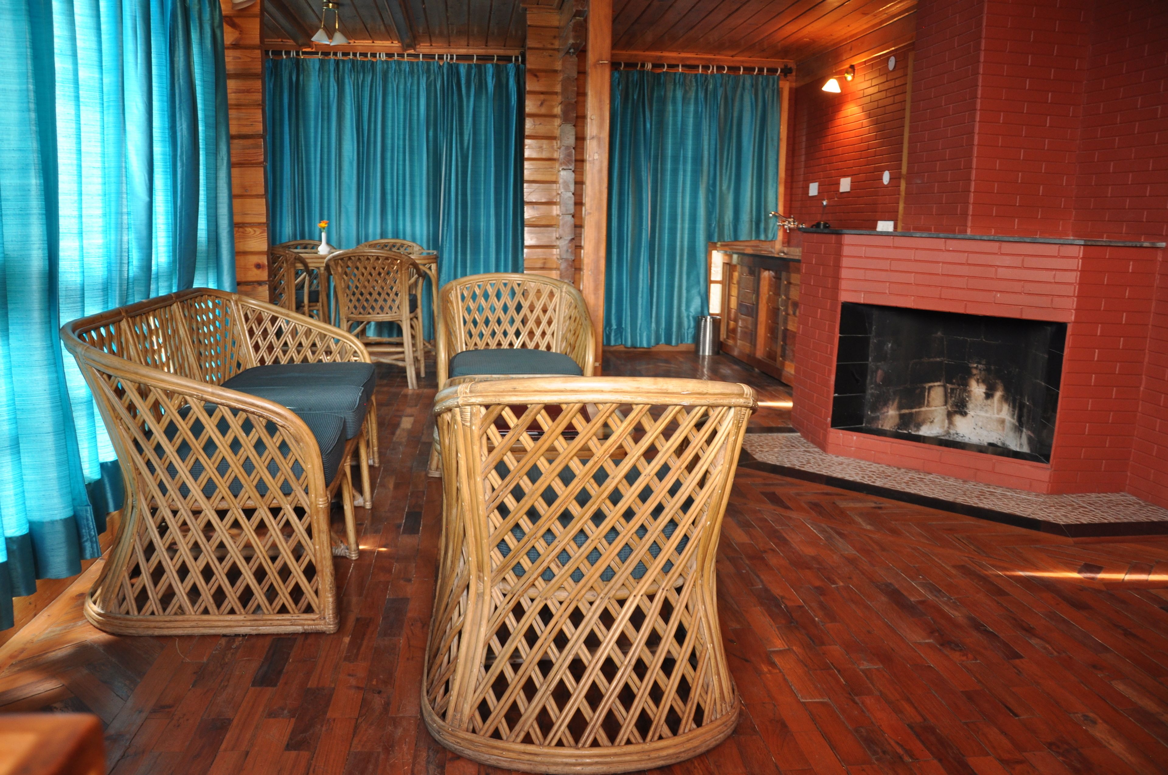 Una habitación acogedora con muebles de mimbre, chimenea y cortinas azules.