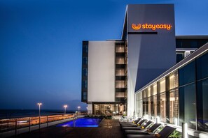 A modern hotel with a pool and outdoor seating area.