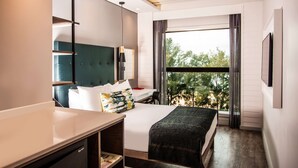 A modern hotel room with a large bed, a desk, and a window with a view of trees. - StayEasy Maputo (Maputo)