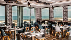 A restaurant with a view of the ocean, featuring modern furniture and large windows. - StayEasy Maputo (Maputo)