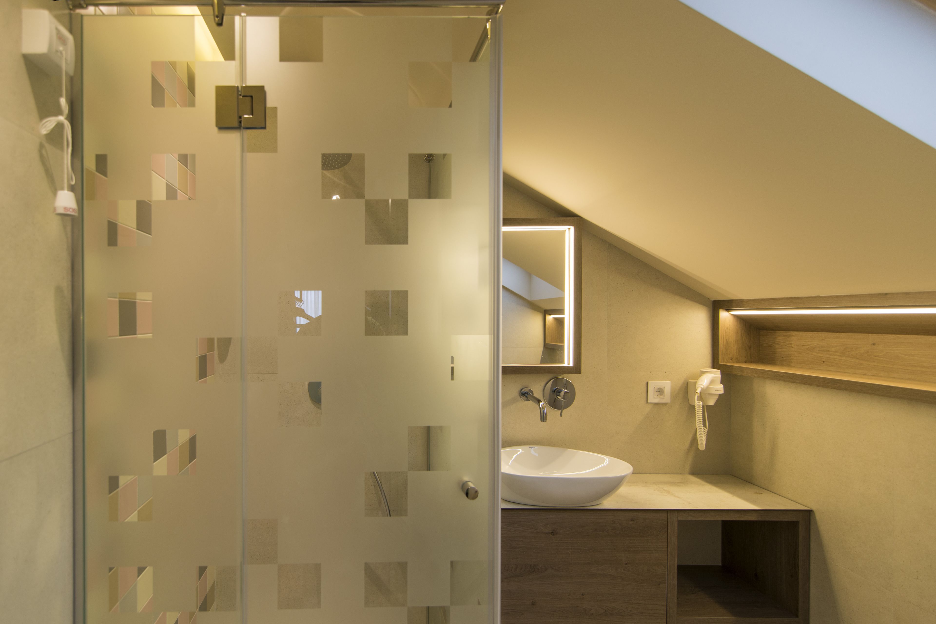 A modern bathroom with a glass shower enclosure, a white sink, and a wooden vanity.
