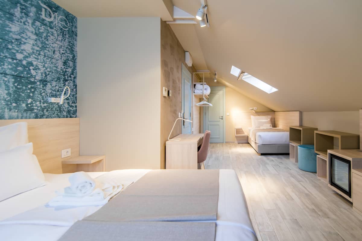 A modern hotel room with a large bed, a desk, and a seating area.