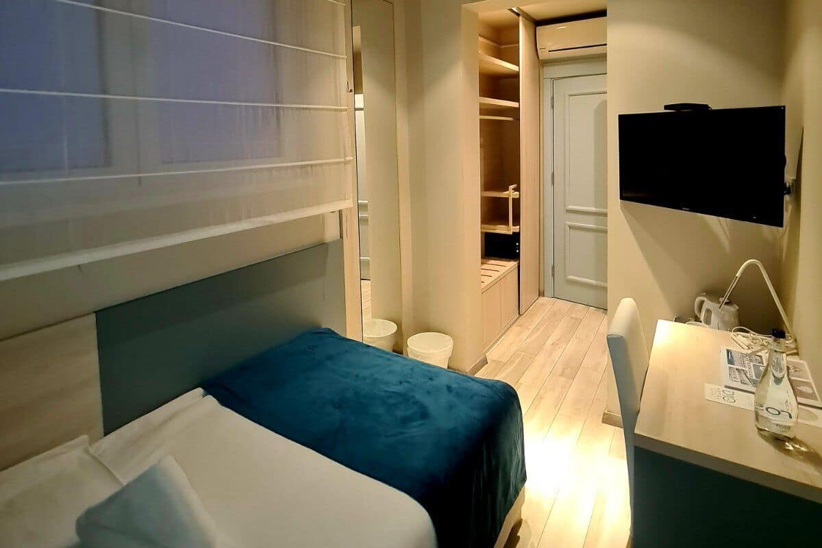 A hotel room with two beds, a desk, a TV, and a wardrobe.