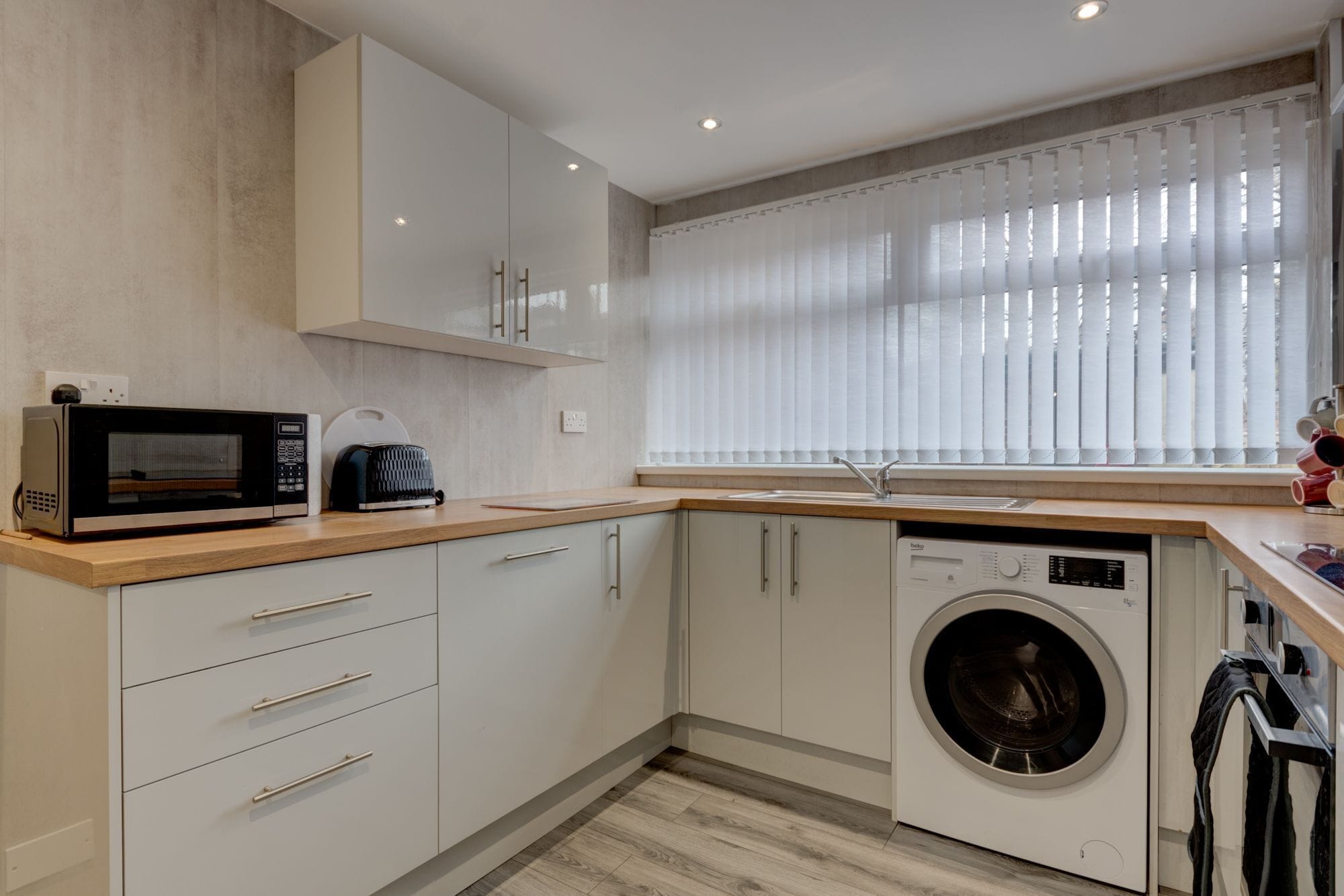 A compact kitchen with a microwave, toaster, and washing machine.
