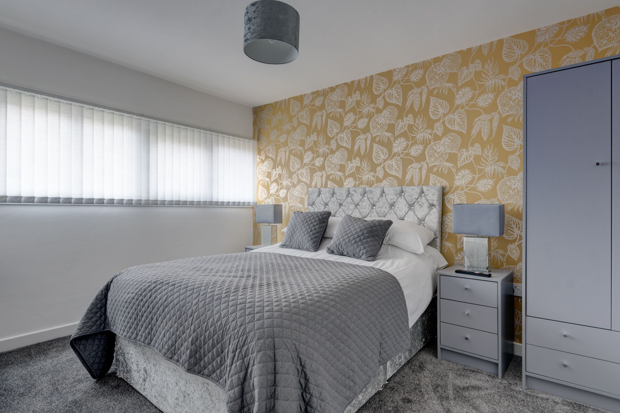 A bedroom with a bed, bedside tables, a wardrobe, and a window with blinds.
