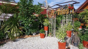 A garden entrance with a sign, potted plants, and a gravel path. - Lampang Bouteak Resort (Lampang)