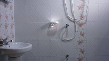 Un baño con lavamanos pedestal, cabezal de ducha de mano y calentador de pared.