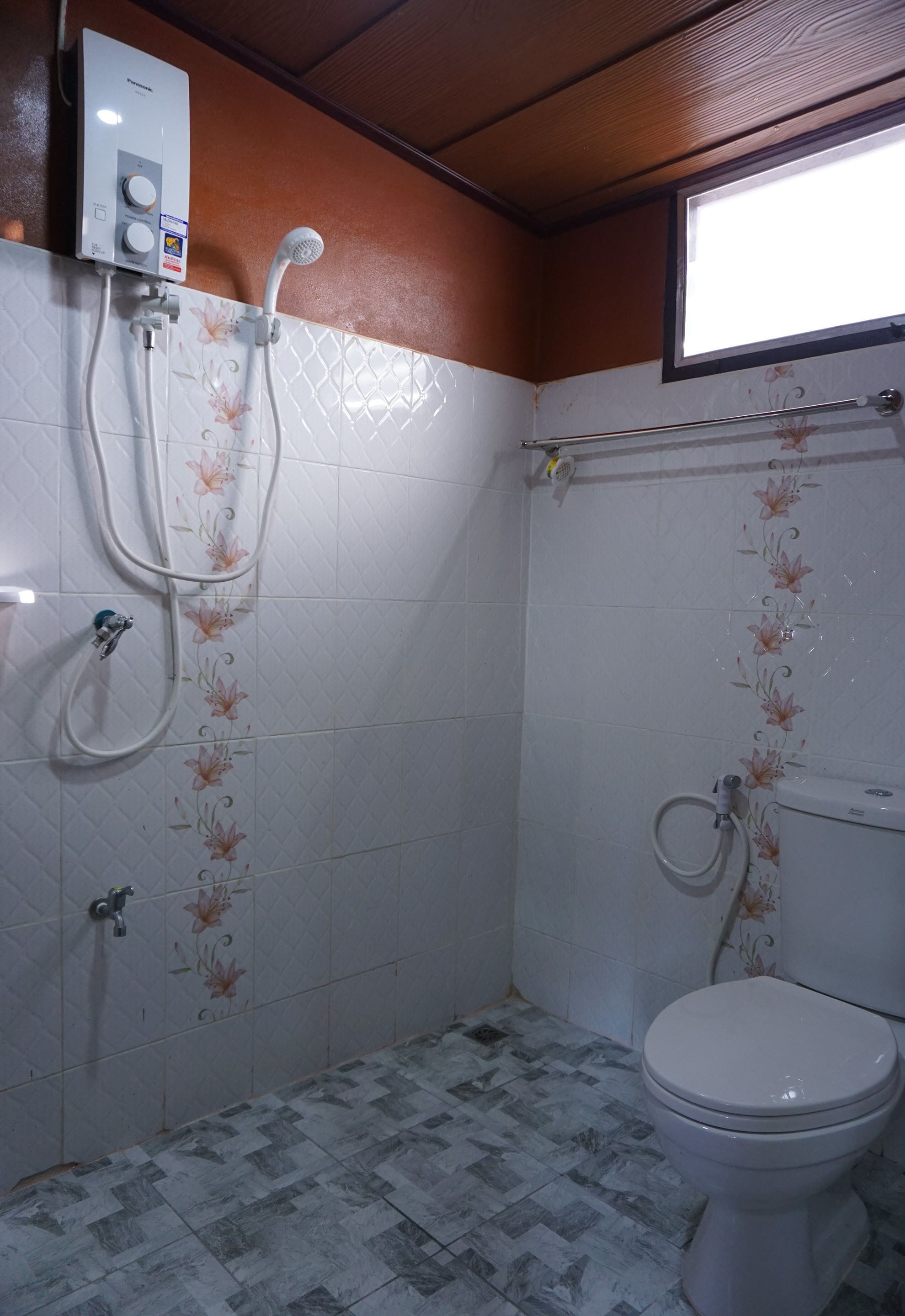 A bathroom with a toilet, a shower, and a wall-mounted heater.