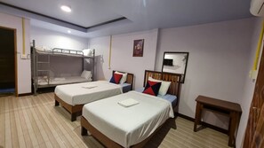 A hotel room with two beds, a bunk bed, a small wooden table, and a mirror on the wall. - Lampang Bouteak Resort (Lampang)