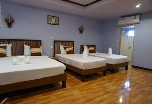 A hotel room with three beds, wooden headboards, and a wooden floor. - Lampang Bouteak Resort (Lampang)