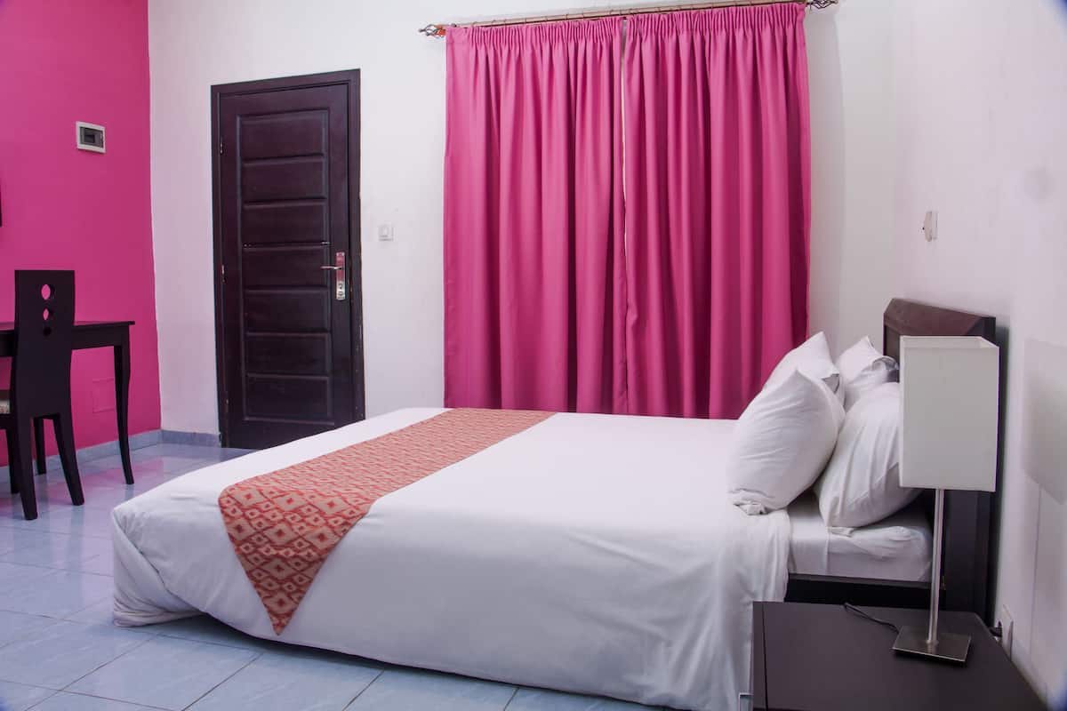 A hotel room with a bed, a desk, and a chair.
