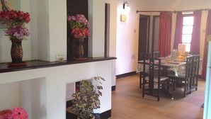 A dining area with a table and chairs, a vase with flowers on the counter, and a hallway leading to a door.