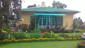A building with a green roof, a large arched window, and a well-maintained garden with various plants and flowers.