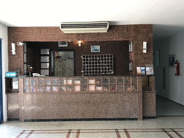 Una recepción con pared de piedra, unidad de aire acondicionado, vitrina de vidrio y extintor.