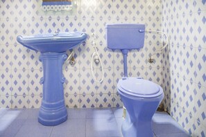 A bathroom with a pedestal sink and a toilet, both in blue, against a tiled wall with a diamond pattern. - GuestHouser 1 BR Cottage 5c31 (Madikeri)