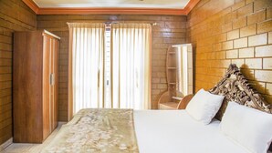 Ein Schlafzimmer mit hölzernem Kopfteil, einem Bett mit weißen Leinen, einem Holzschrank und einem Fenster mit Vorhängen.