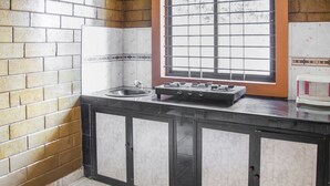 Eine Küche mit Gaskochfeld, Spüle und einem Fenster mit Gittermuster.