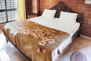 A bed with a floral bedspread, a wooden headboard, and a brick wall. - GuestHouser 1 BR Cottage 5c31 (Madikeri)