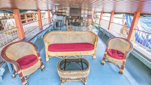 A covered deck with wicker furniture, a table, and chairs. - GuestHouser 3 BHK Houseboat 147b (Ambalapuzha)