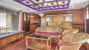 A room with a wooden ceiling, a glass table, wicker furniture, and a wooden cabinet. - GuestHouser 3 BHK Houseboat 147b (Ambalapuzha)