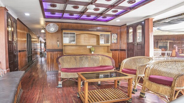 A room with a wooden ceiling, a large fan, wicker furniture, and a glass table. - GuestHouser 3 BHK Houseboat 147b (Ambalapuzha)