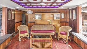A room with a wooden ceiling, a central sofa with red cushions, and a small table. - GuestHouser 3 BHK Houseboat 147b (Ambalapuzha)