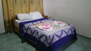 Una cama individual con colcha estampada y manta a rayas azules y blancas.