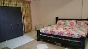 A bedroom with a bed, a wardrobe, and a small table. - Permiss Ka Hotel (Accra)