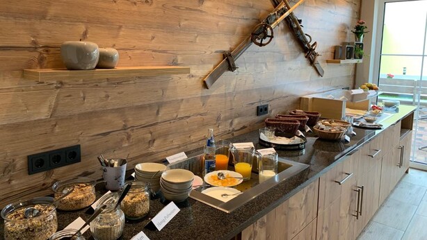 A breakfast bar with various food items and a ski rack on the wall. - Hotel Dachsbaude & Kammbaude (Neuhausen)