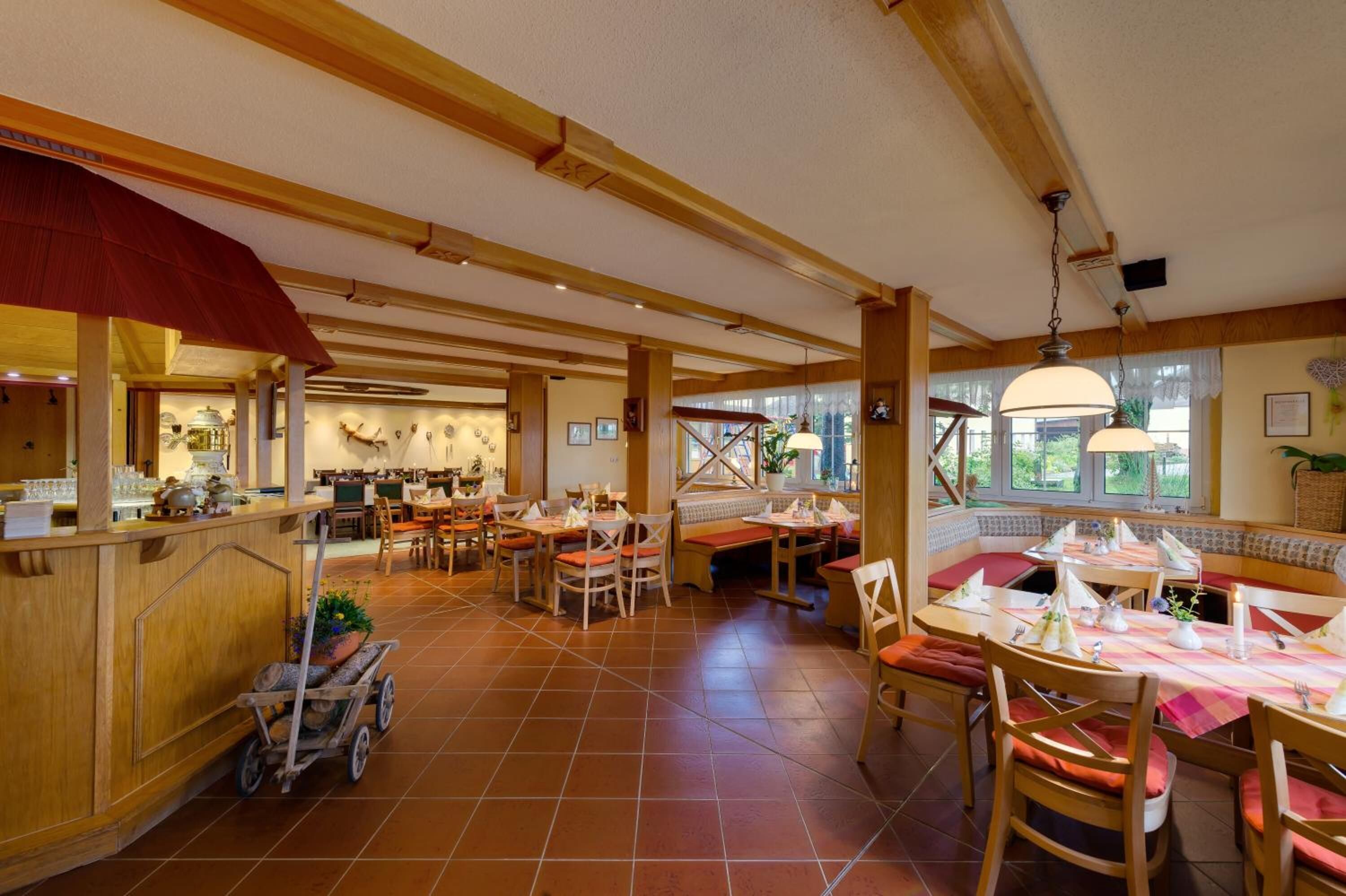 Un restaurant doté de poutres en bois, d’un sol en terre cuite et proposant différents types de sièges, notamment des tables et des banquettes.