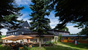 A large building with a balcony and outdoor seating area. - Hotel Dachsbaude & Kammbaude (Neuhausen)