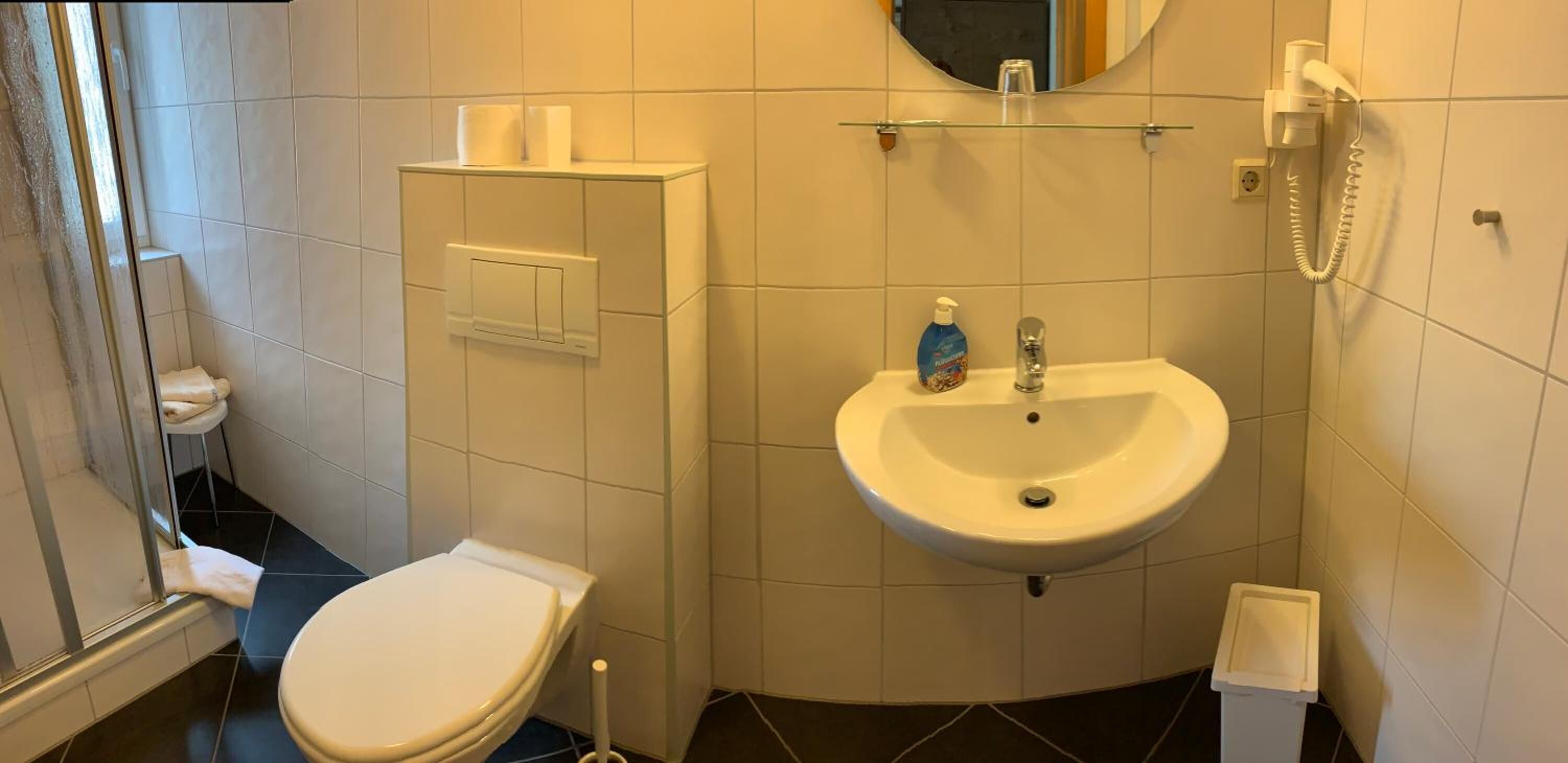 A small bathroom with a toilet, a sink, a mirror, and a telephone.