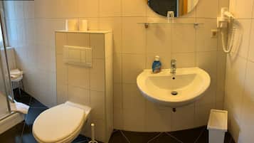A small bathroom with a toilet, a sink, a mirror, and a telephone.