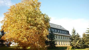 A large building with a flat roof and multiple windows, surrounded by trees and grass.
