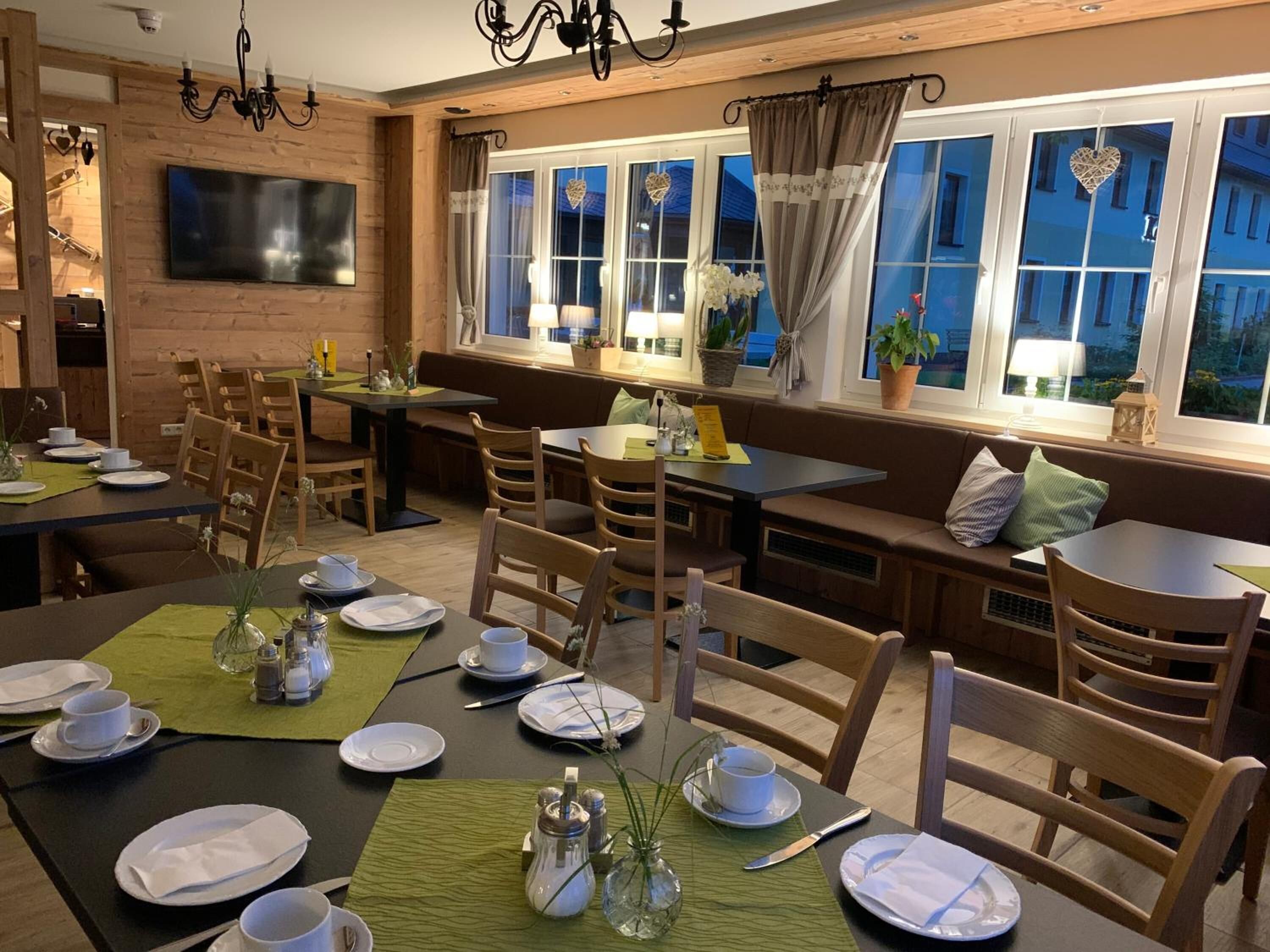 Un restaurant chaleureux avec des murs en bois, de nombreuses tables et des sièges confortables.
