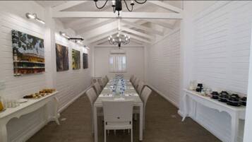 Comedor con una mesa larga, paredes blancas y una araña.