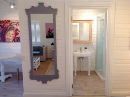 Un baño con un lavamanos blanco, espejo y suelo de madera.