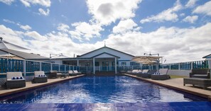 Una piscina al aire libre, sillones reclinables de piscina