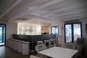 Un bar moderno con barra, taburetes y mobiliario de mimbre.
