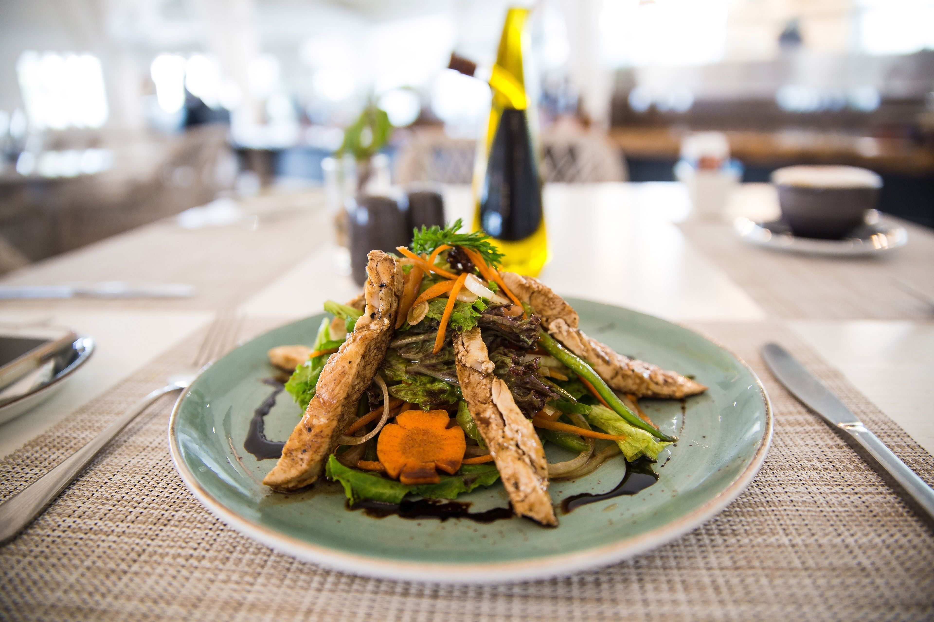 A plate of food with a bottle of olive oil and a cup in the background.