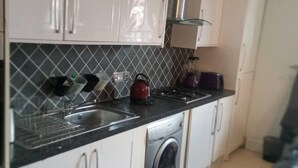 Een keuken met een roestvrijstalen spoelbak, een waterkoker en een blender op het aanrecht.