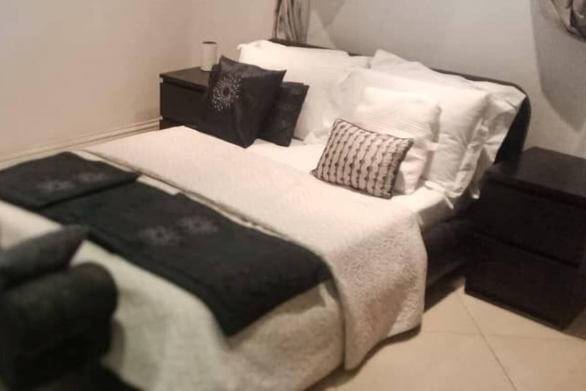 A neatly arranged bedroom with a bed, bedside tables, and a nightstand.