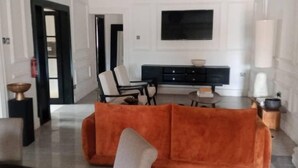 Een moderne woonkamer met een bank, stoelen en een televisie.