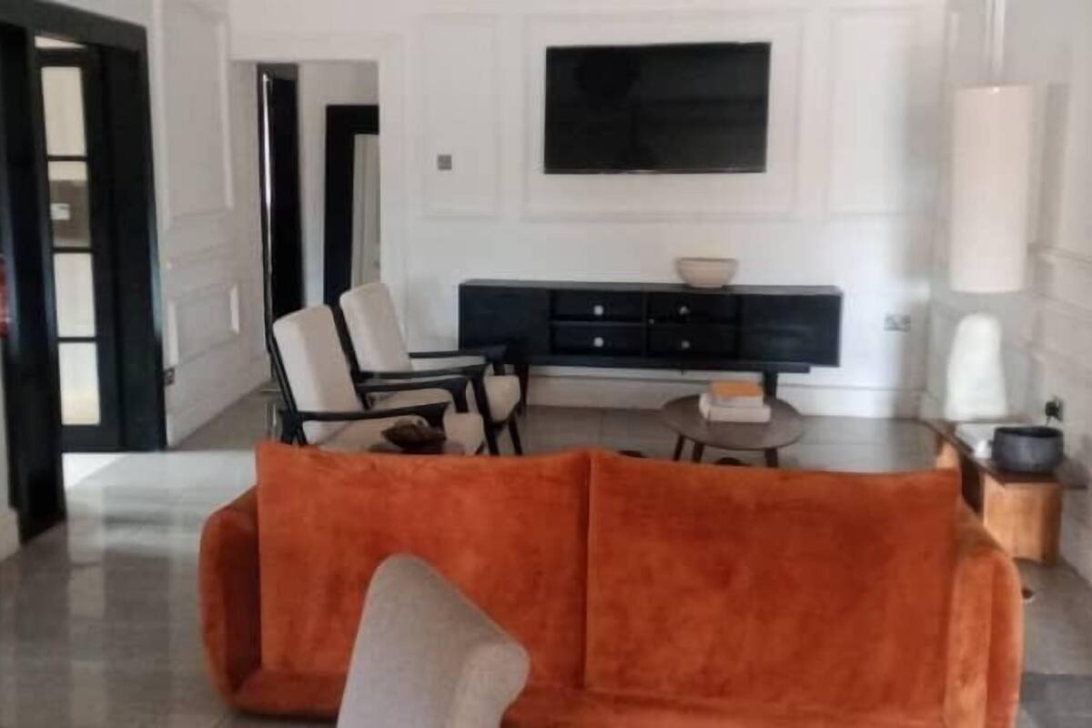 A modern living room with a sofa, chairs, and a TV.
